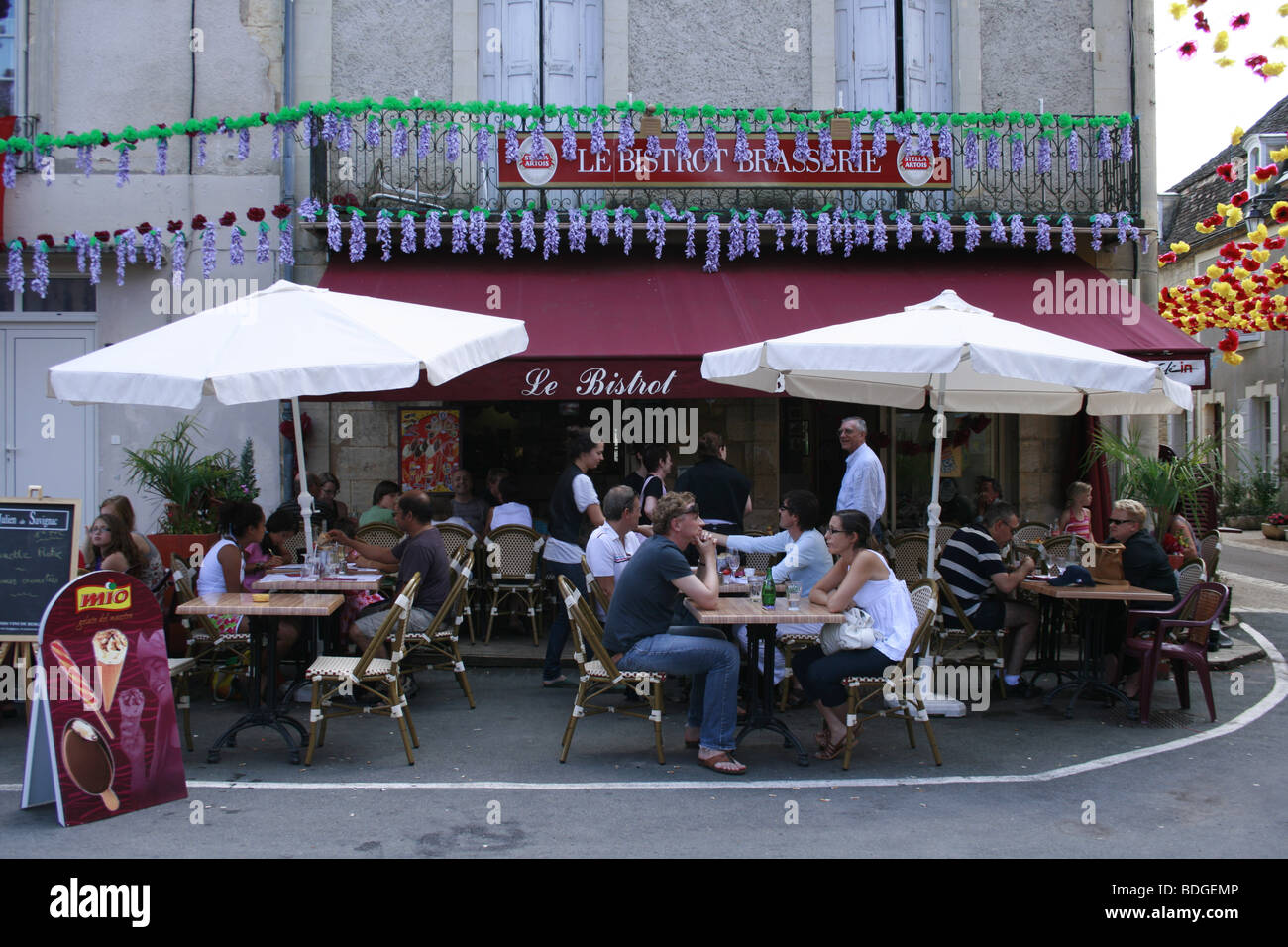 Les personnes appréciant le déjeuner sur la terrasse d'un café/restaurant à Beaumont du Périgord, France Banque D'Images