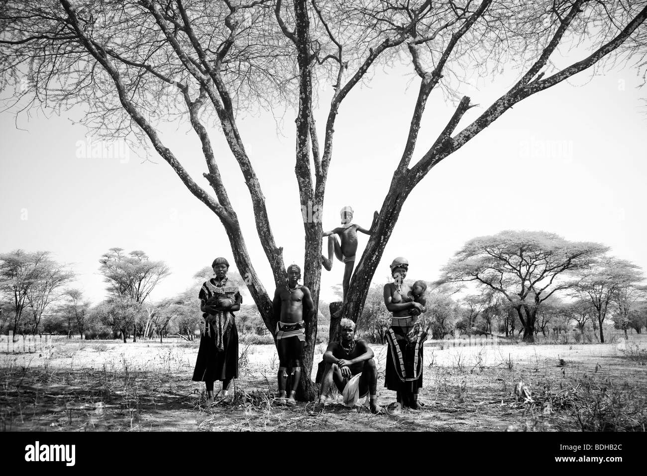 Portrait d'un groupe d'autochtones vêtus de costumes traditionnels, primitifs posés sous un large arbre ramifié dans desert setti Banque D'Images