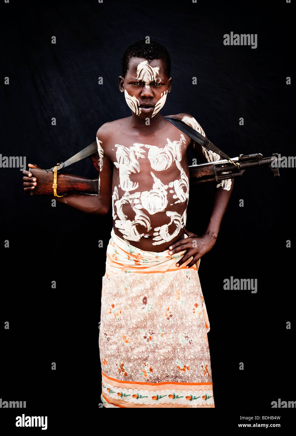 Portrait d'un jeune homme en costume traditionnel et décoration corps posés devant un tissu noir. Banque D'Images