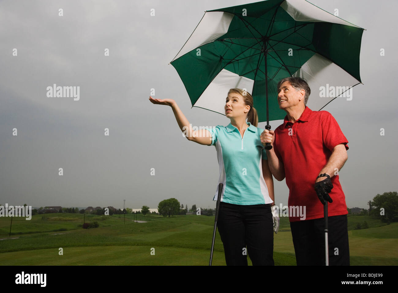 Père et fille sur le cours de golf la tenue d'un grand parapluie Banque D'Images