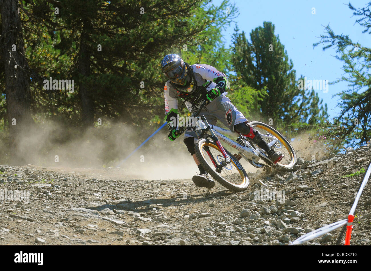 Une descente en vélo de montagne tourne à la vitesse sur un sentier rocheux dans un casque intégral et blindé à Pila dans les Alpes italiennes Banque D'Images