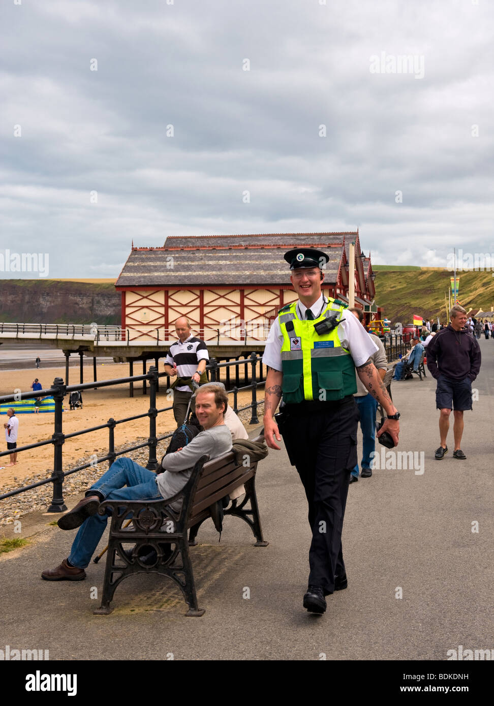 Agent de police communautaire à marcher le long de la promenade de bord de mer Banque D'Images