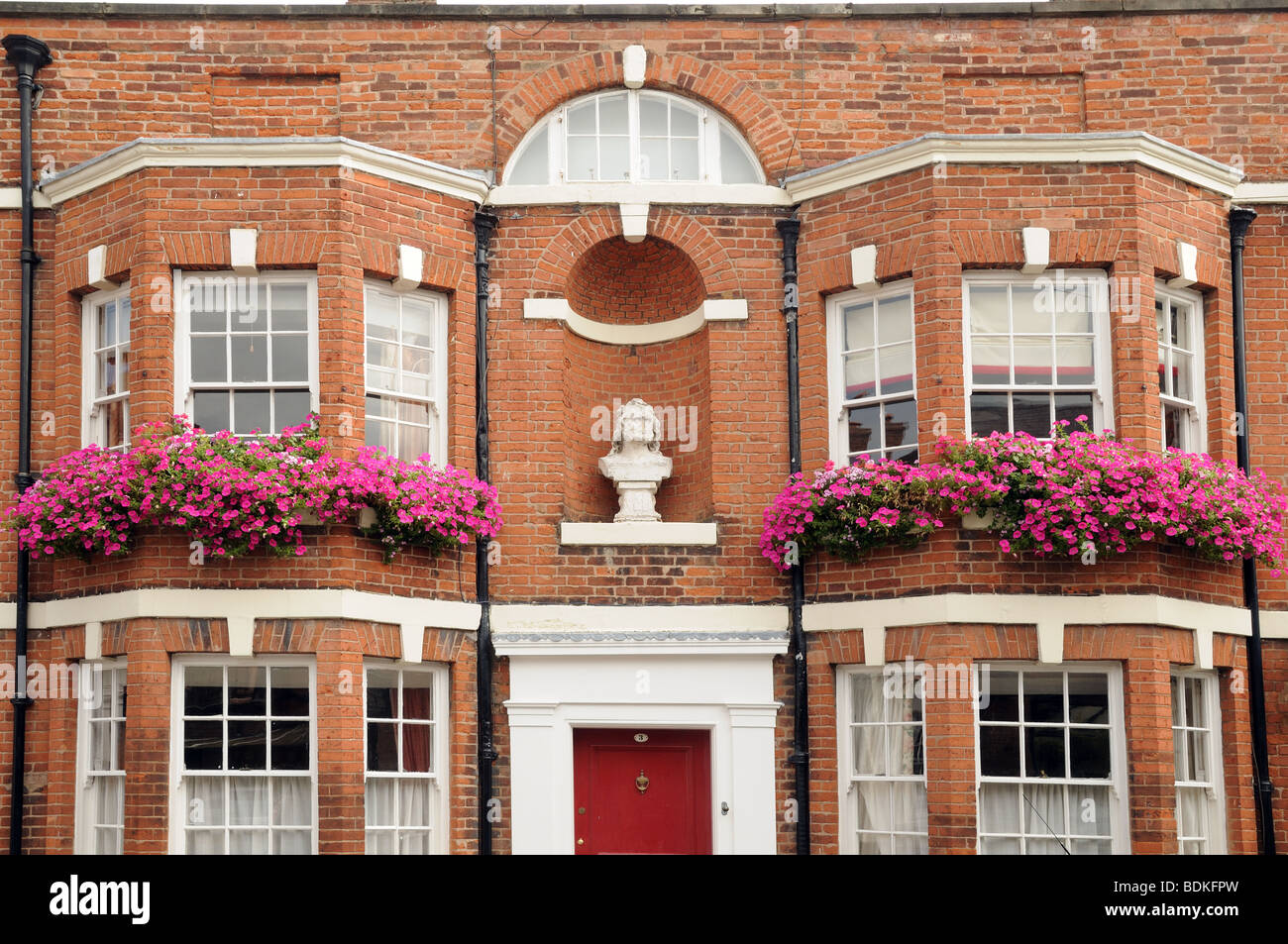 Vieille maison construite en brique rouge avec des baies vitrées et des fenêtres sur la rue pétunias roses Nouvelle Angleterre Warwick Banque D'Images