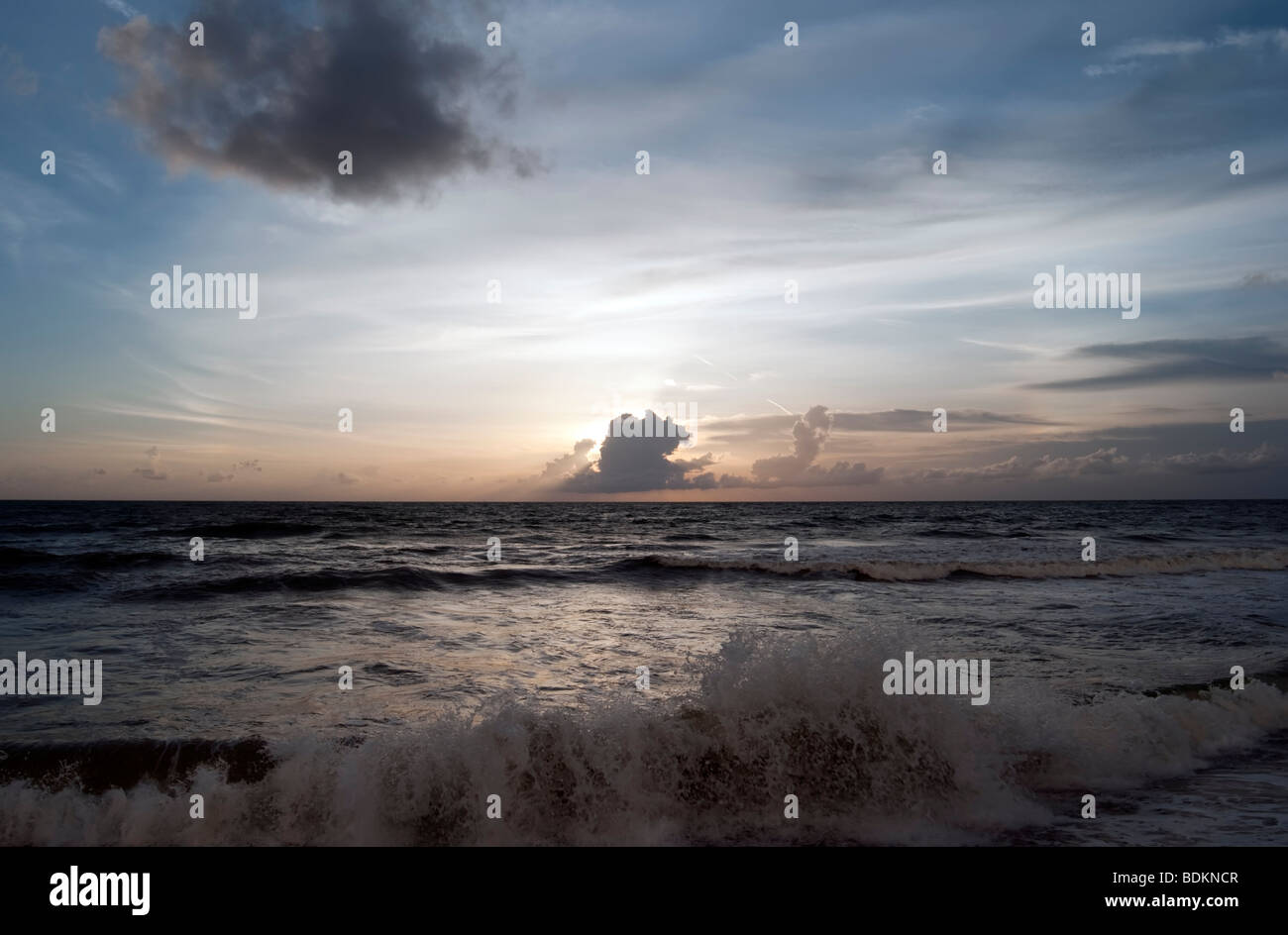Les vagues au coucher du soleil & Cloud. Vagues se brisant sur le rivage de l'atmosphère solaire couvre de nuages Banque D'Images