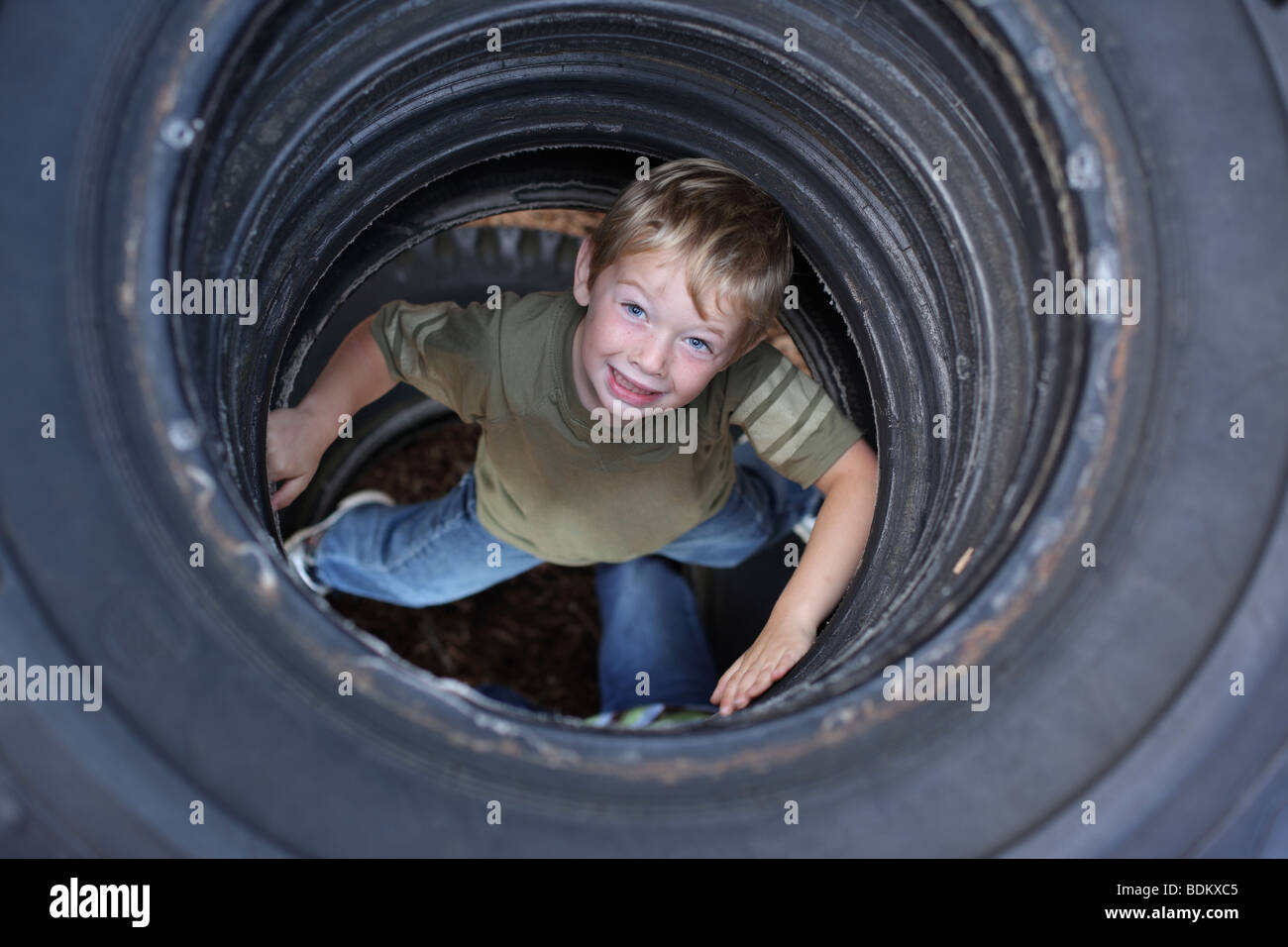 Jeune garçon dans les pneus avec park Banque D'Images
