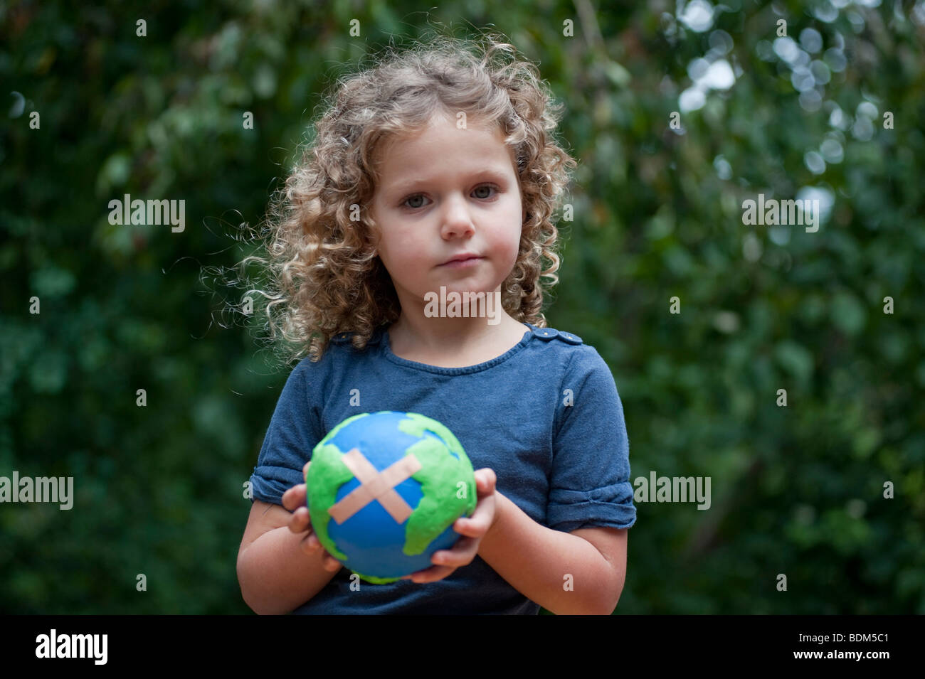 Jeune fille tenant une maquette d'un malade la planète Terre avec une aide de bande attaché Banque D'Images