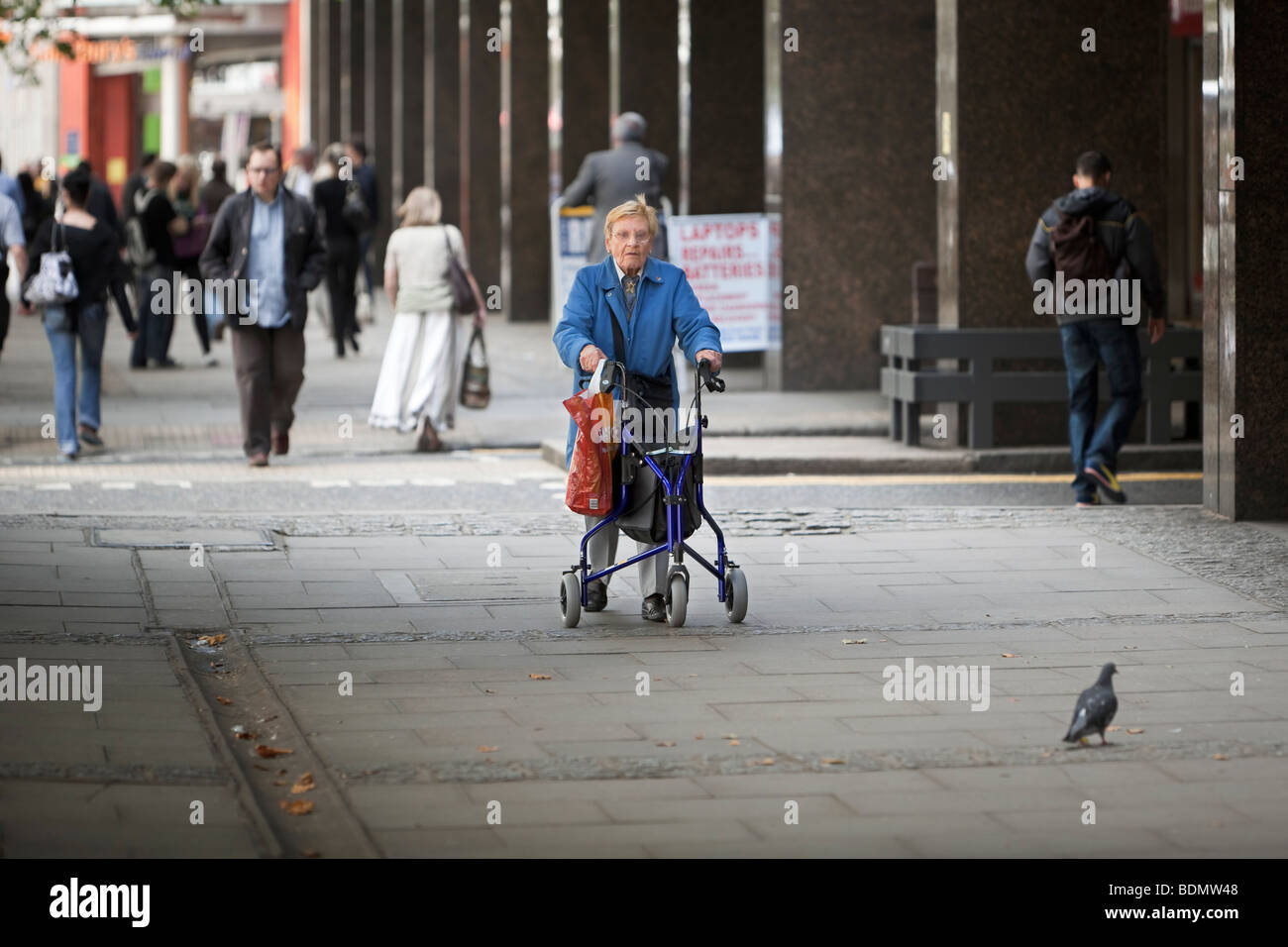 Une femme âgée partiellement désactivé à l'aide d'un châssis à roues marche dans le centre de Londres, UK Banque D'Images