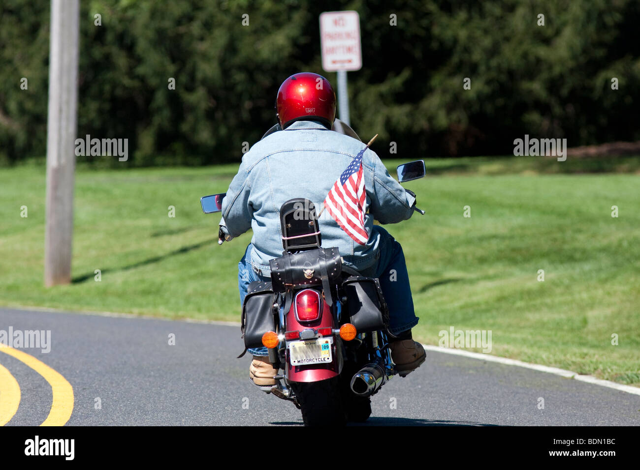 Moto Moto rider avec un drapeau américain attaché à l'sissy bar. Casque rouge et chemise en jean. Banque D'Images