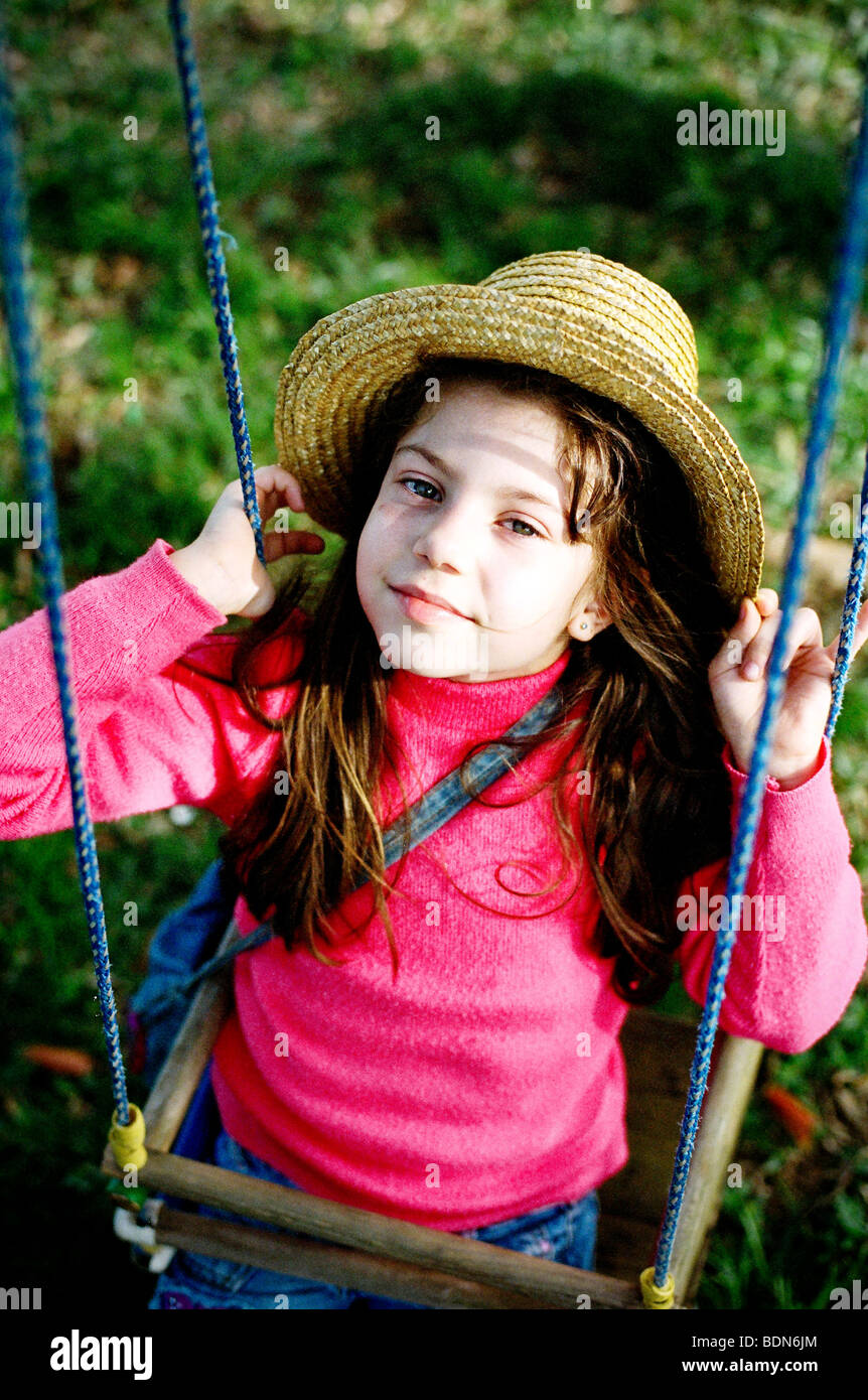 Girl wearing hat sur rose et jouer sur la balançoire Banque D'Images