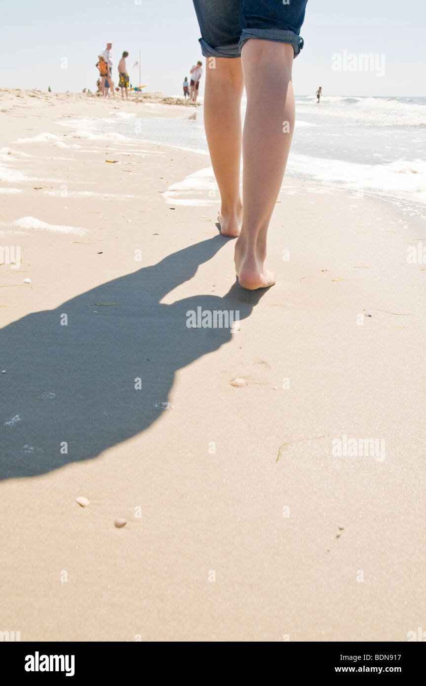 Femme se promenant le long d'une plage Banque D'Images