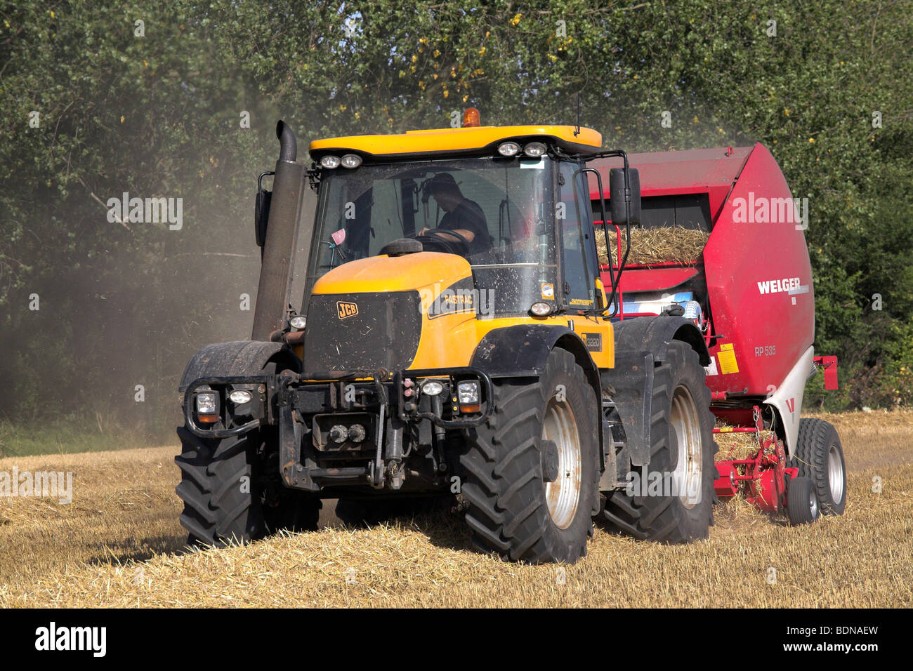 Le tracteur et de paille dans un champ de travail de la ramasseuse-presse Banque D'Images