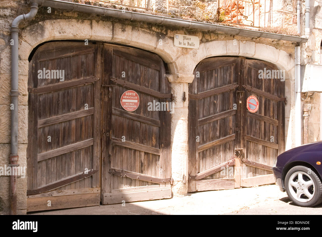 Paire de portes de garage en bois dans un bâtiment en pierre dans la ville de Puy Leveque, français pas de panneaux de stationnement Banque D'Images