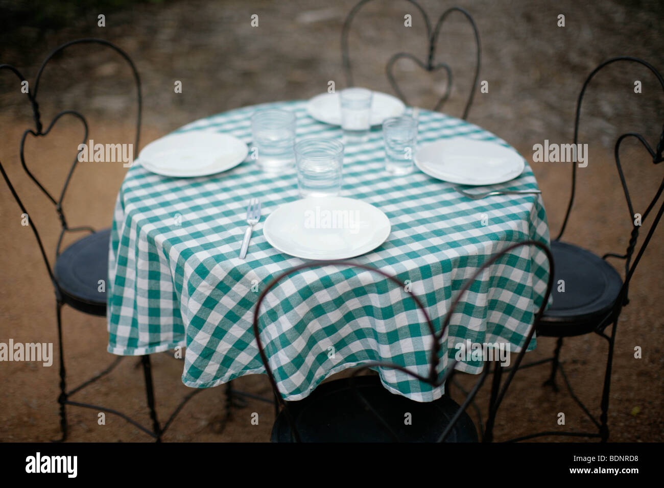 Table et chaises avec nappe à carreaux et couverts Banque D'Images