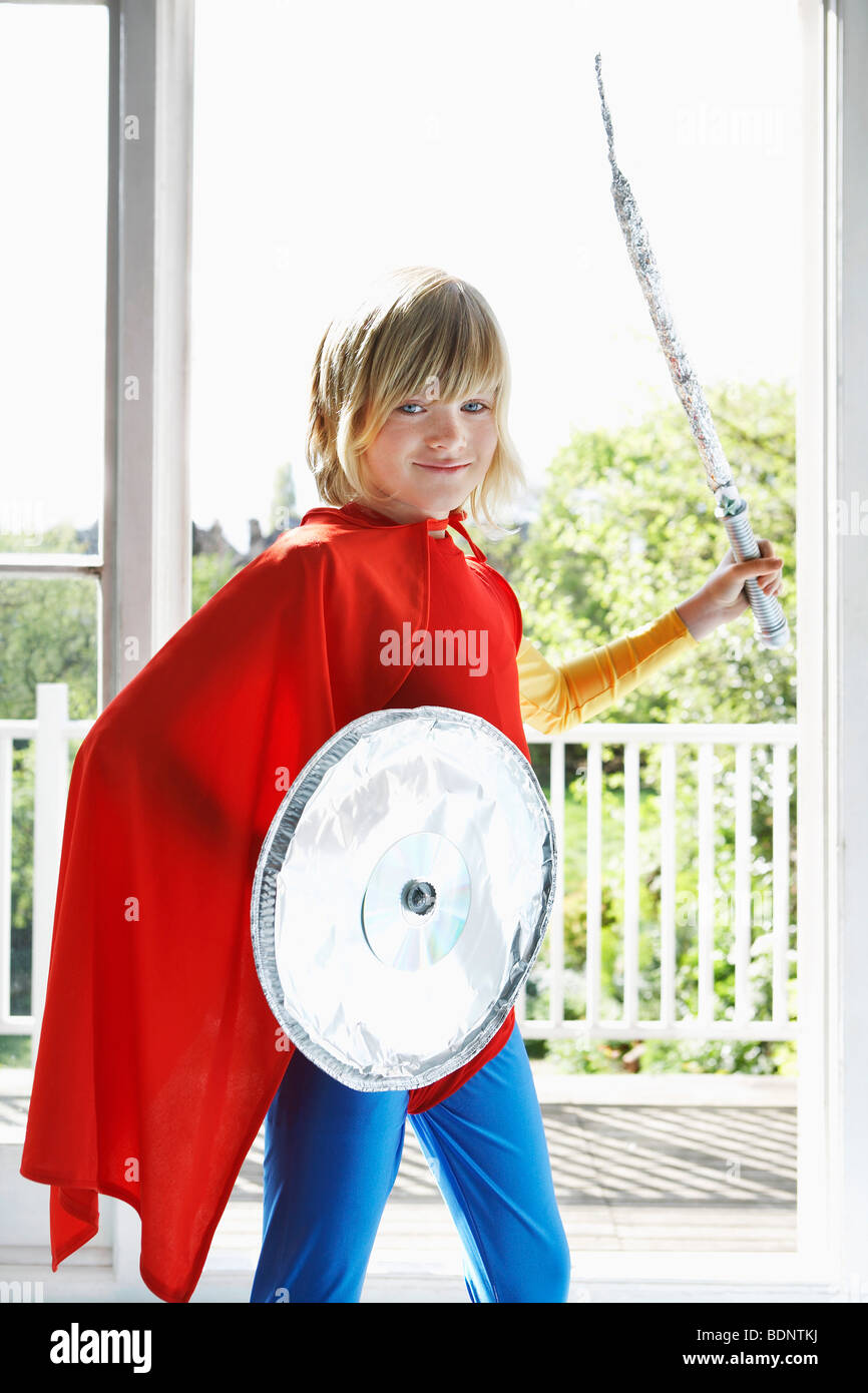 Portrait de jeune garçon (7-9) en costume de super-héro holding toy le bouclier et l'épée, smiling Banque D'Images