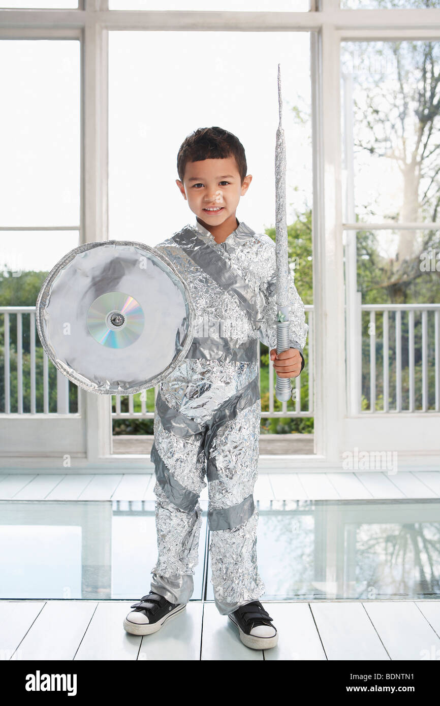Portrait de jeune garçon (5-6) posant dans du papier aluminium à l'intérieur, costume chevalier Banque D'Images