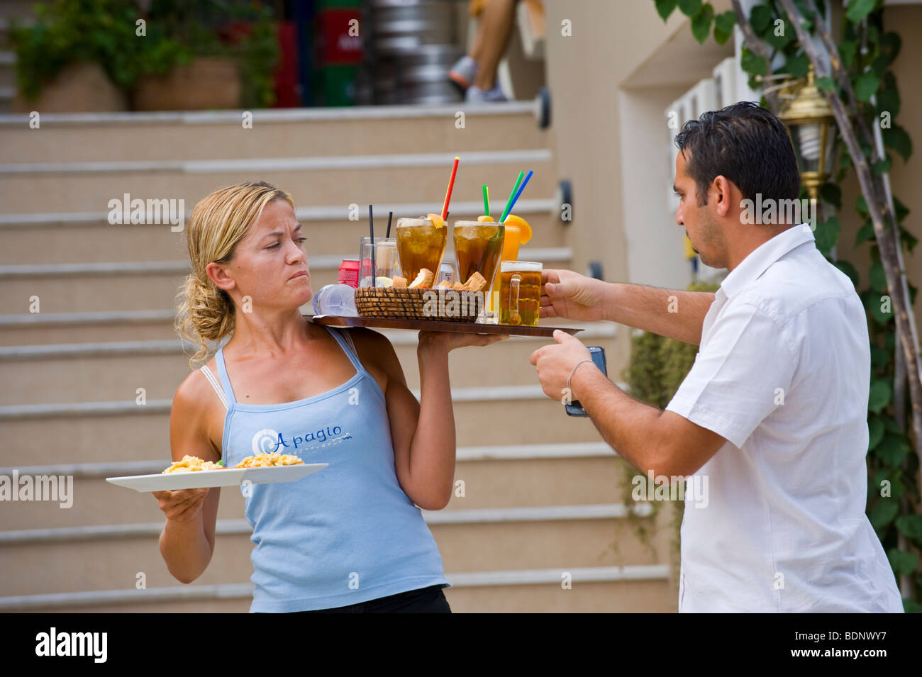 Serveurs servant de la nourriture et des boissons au restaurant à Fiskardo sur la Méditerranée grecque île de Céphalonie, Grèce GR Banque D'Images