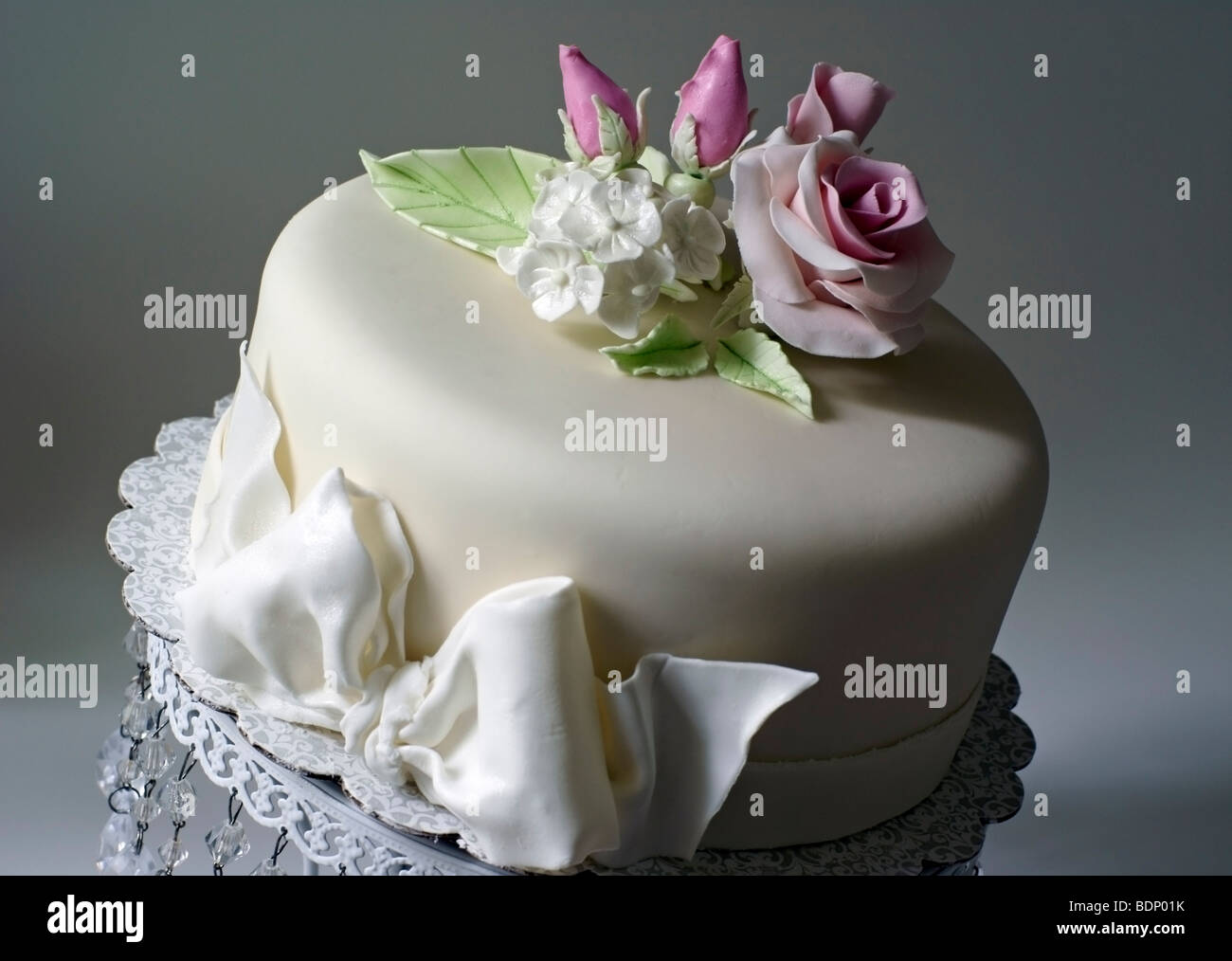 Gâteau recouvert de fondant et décoré avec des roses rose Banque D'Images