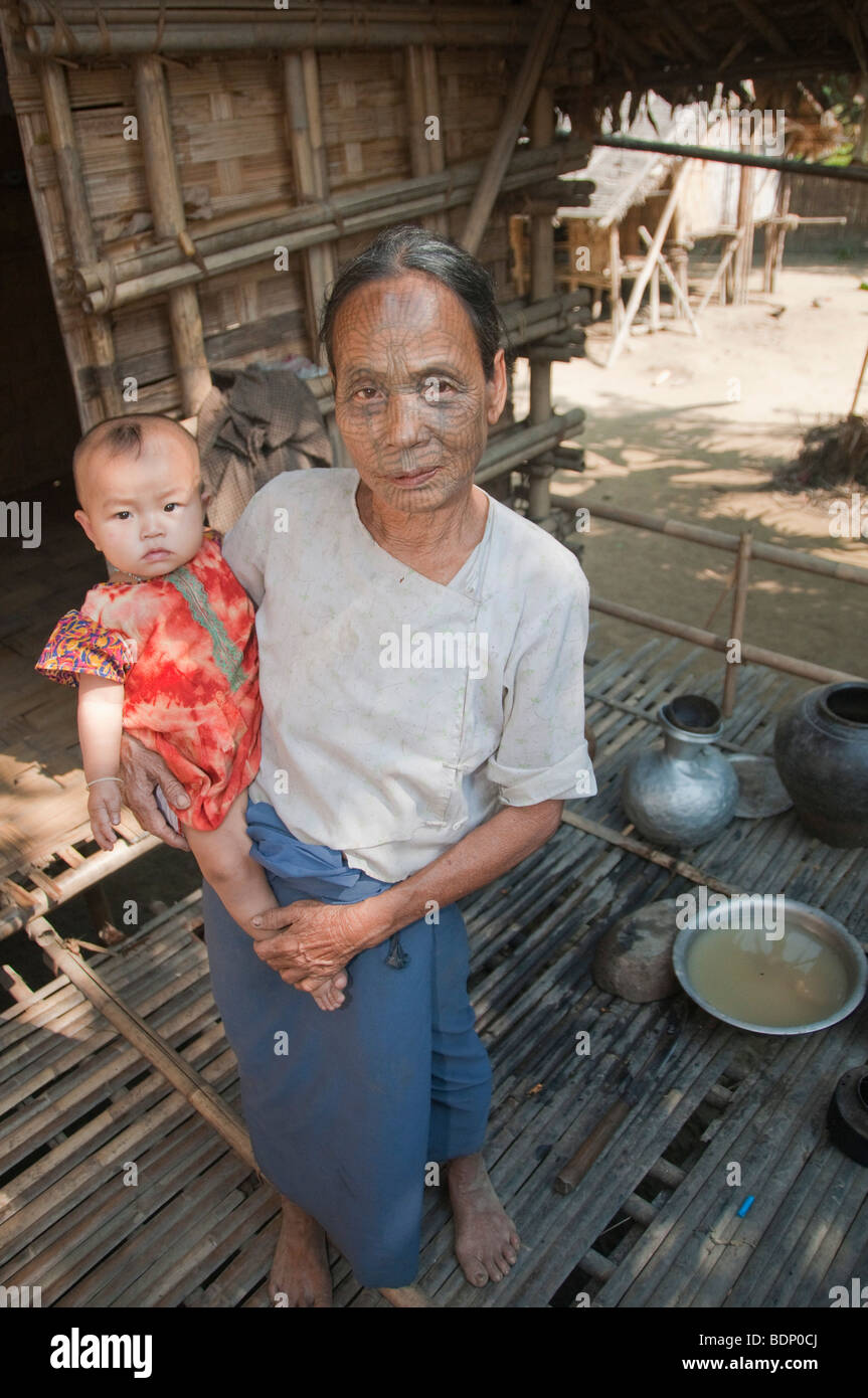Tribu menton Femme avec visages tatoués holding sa petite-fille dans un Le-Mro Chin village sur la rivière près de Mrauk U, roi de Rakhine Banque D'Images