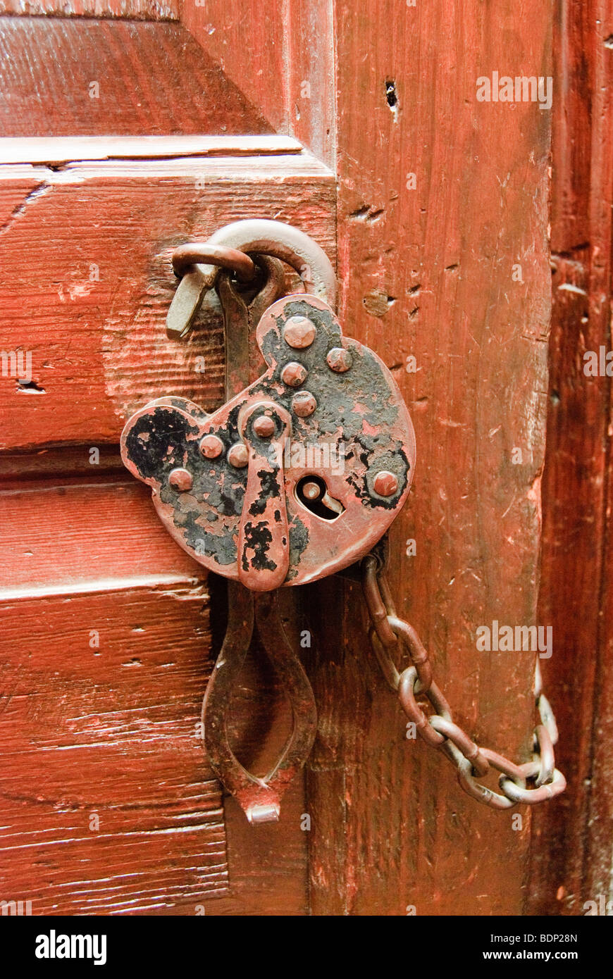Vieux et cadenas rouillé avec chaîne à une porte rouge Banque D'Images