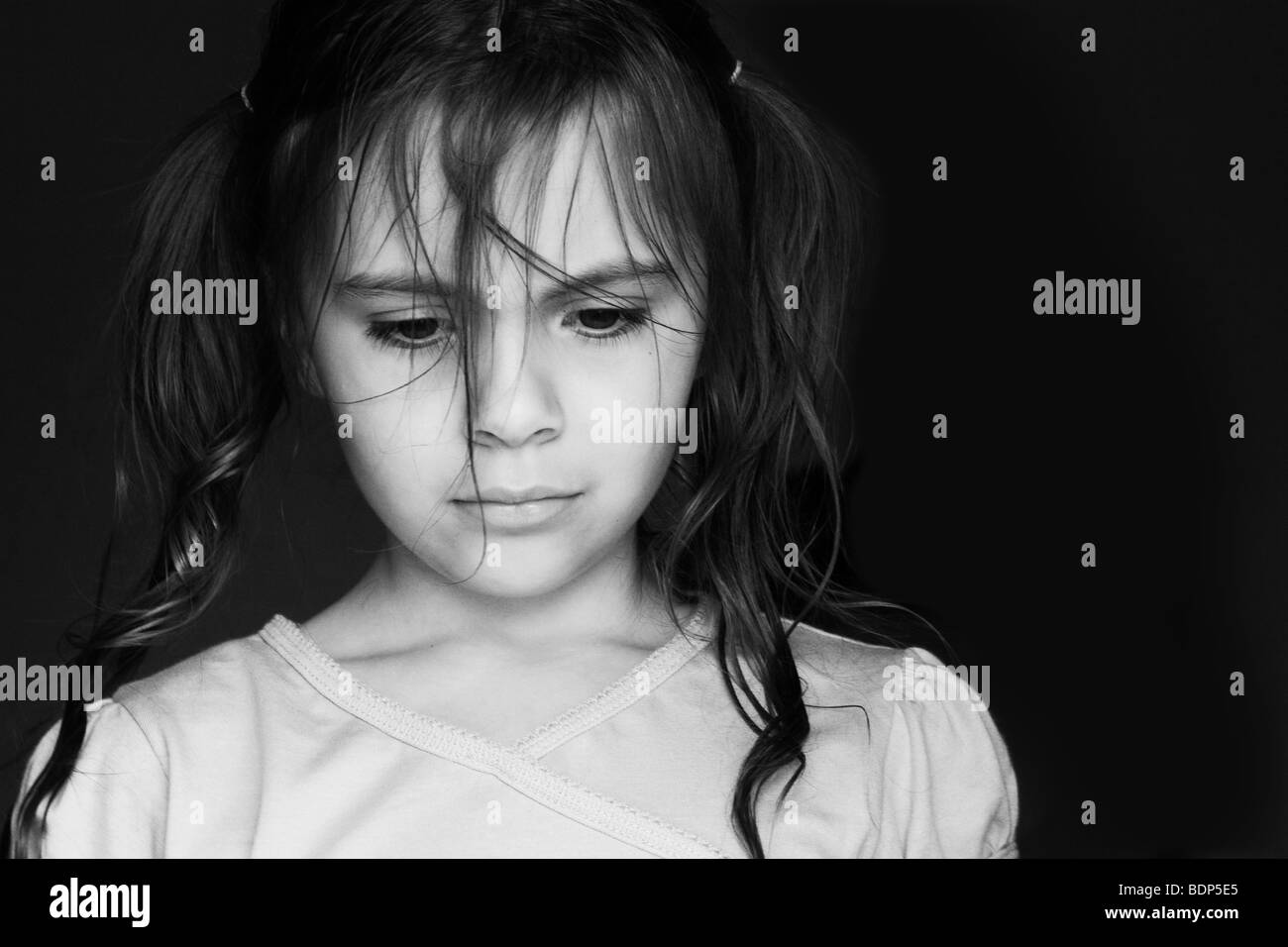 Image en noir et blanc d'une jeune fille avec ses cheveux en amorces à la triste Banque D'Images