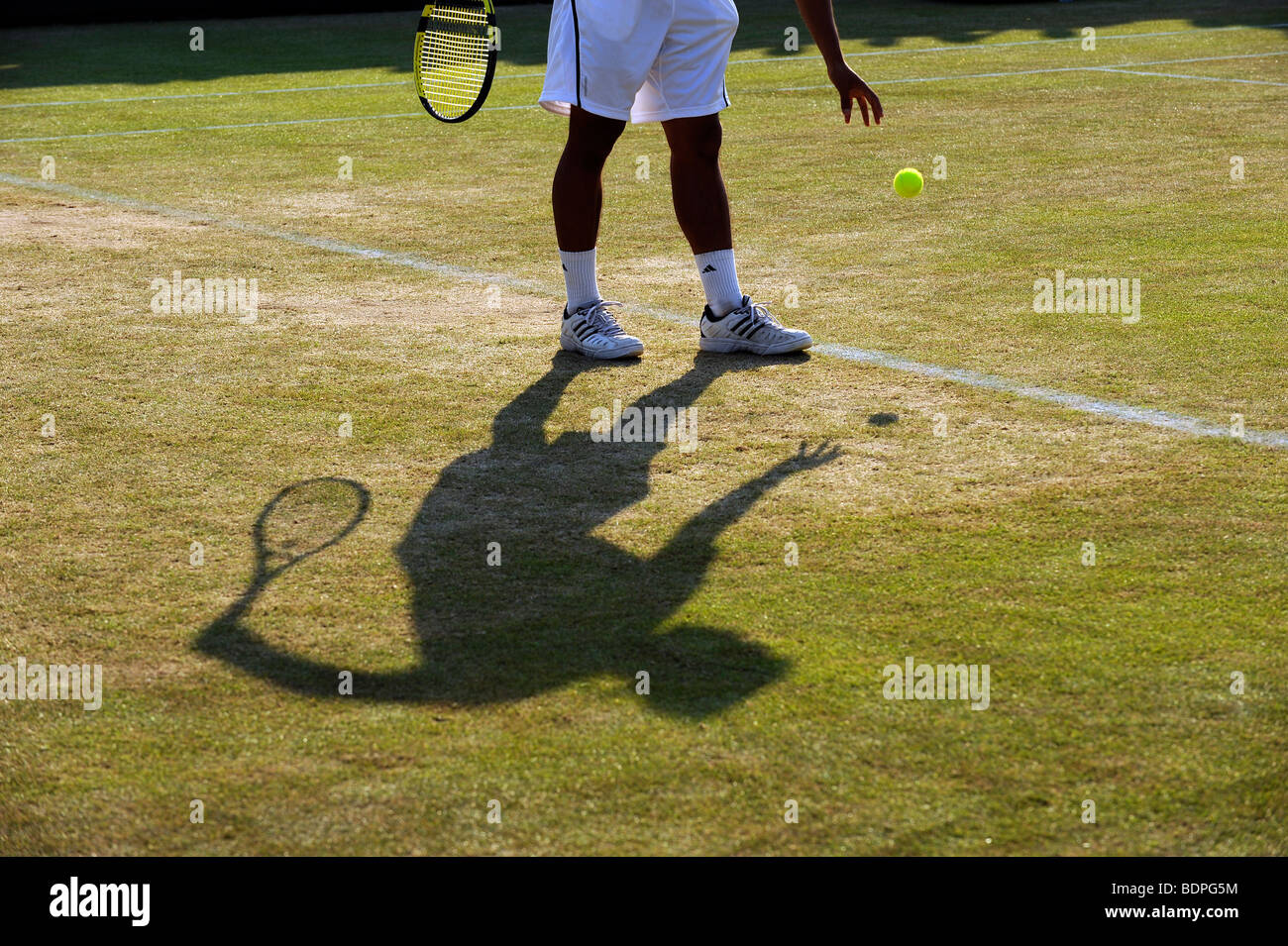 Un joueur et l'ombre qu'il fait rebondir le ballon avant de servir au cours de l'édition 2009 des Championnats de tennis de Wimbledon Banque D'Images