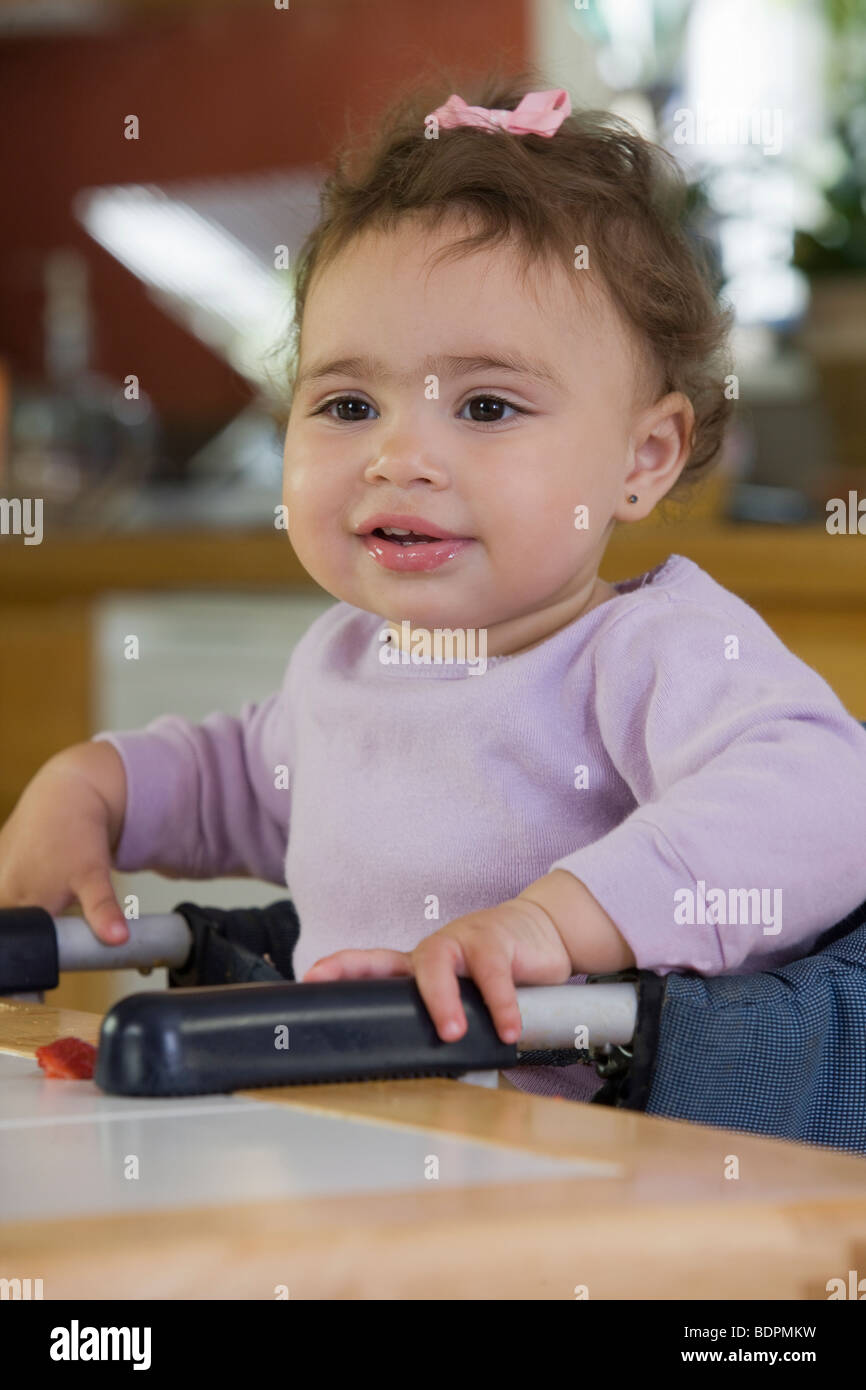 Hispanic baby girl sitting sur une chaise haute Banque D'Images