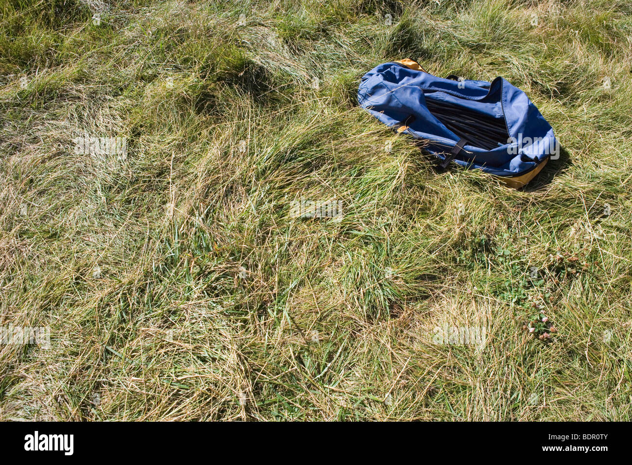 Un sac contenant une tente et des poteaux est assis sur l'herbe dans un camping Banque D'Images