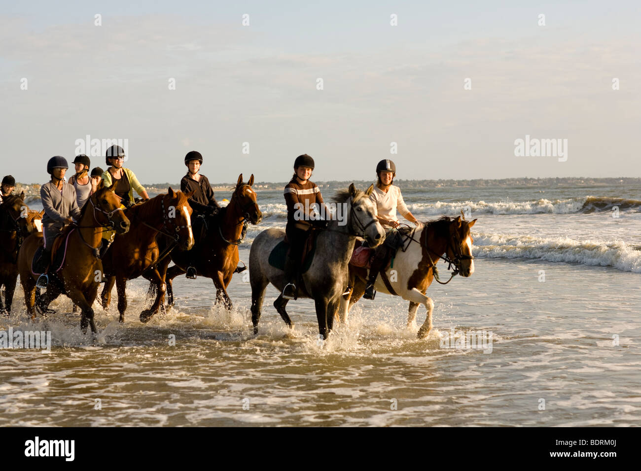 Un centre équestre va pour un hack sur la plage et dans les vagues. Les cavaliers sont de tous les âges et capacités. Banque D'Images