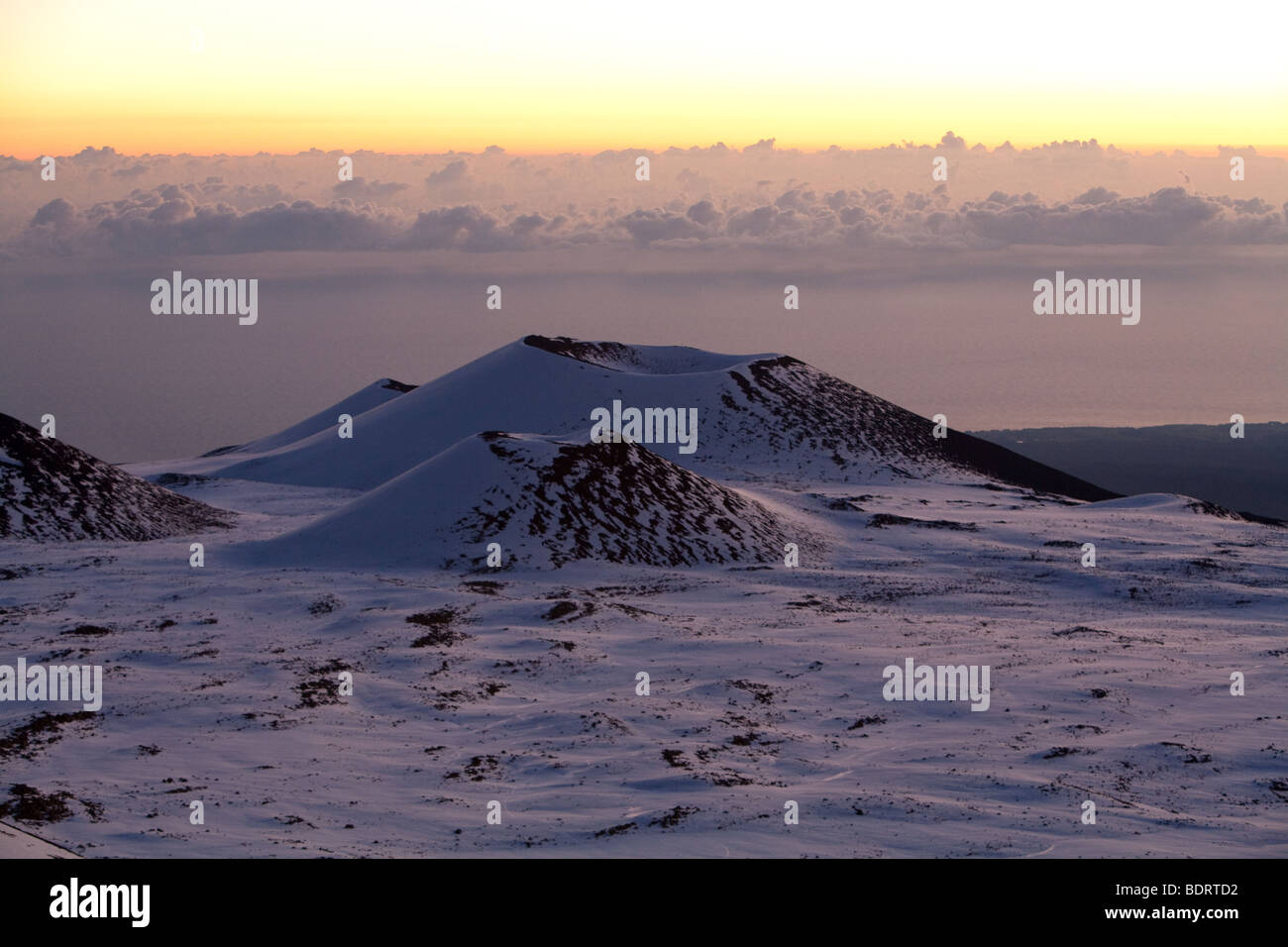 Des cônes sont vus dans la distance entre le sommet du Mauna Kea, à Hawaii, au lever du soleil. Banque D'Images