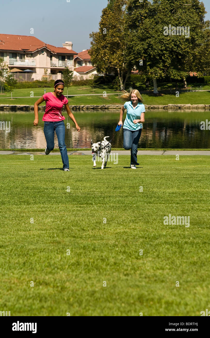 Deux adolescentes accrocher à traîner ensemble et Hispaniques Caucasian teenage girls 14 ans courir chien Dalmatien/USA USMR © Myrleen Pearson Banque D'Images