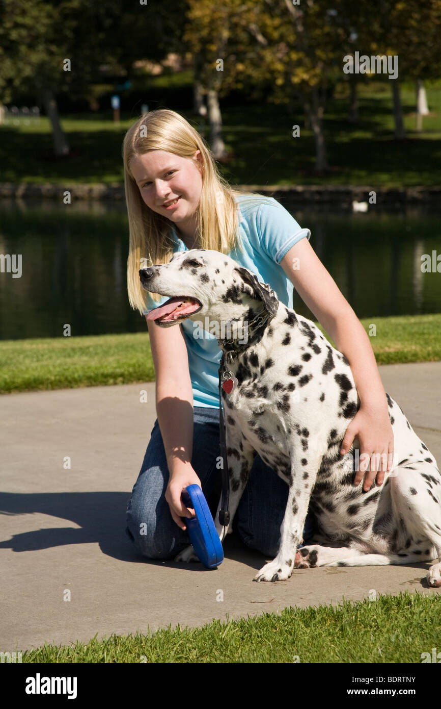 Caucasian girl 11-13 ans ans posant son chien dalmatien au cours de marche propriétaire enfant jouant jouer joue côté profil chiens vue avant © Myrleen Pearson Banque D'Images