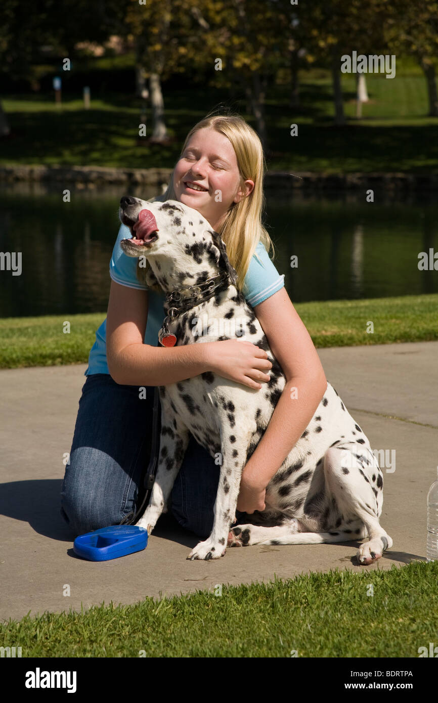 Girl hugging dog enfant 11-13 ans ans jouant propriétaire de chien dalmatien montrer de l'affection side Voir le profil MR © Myrleen Pearson Banque D'Images