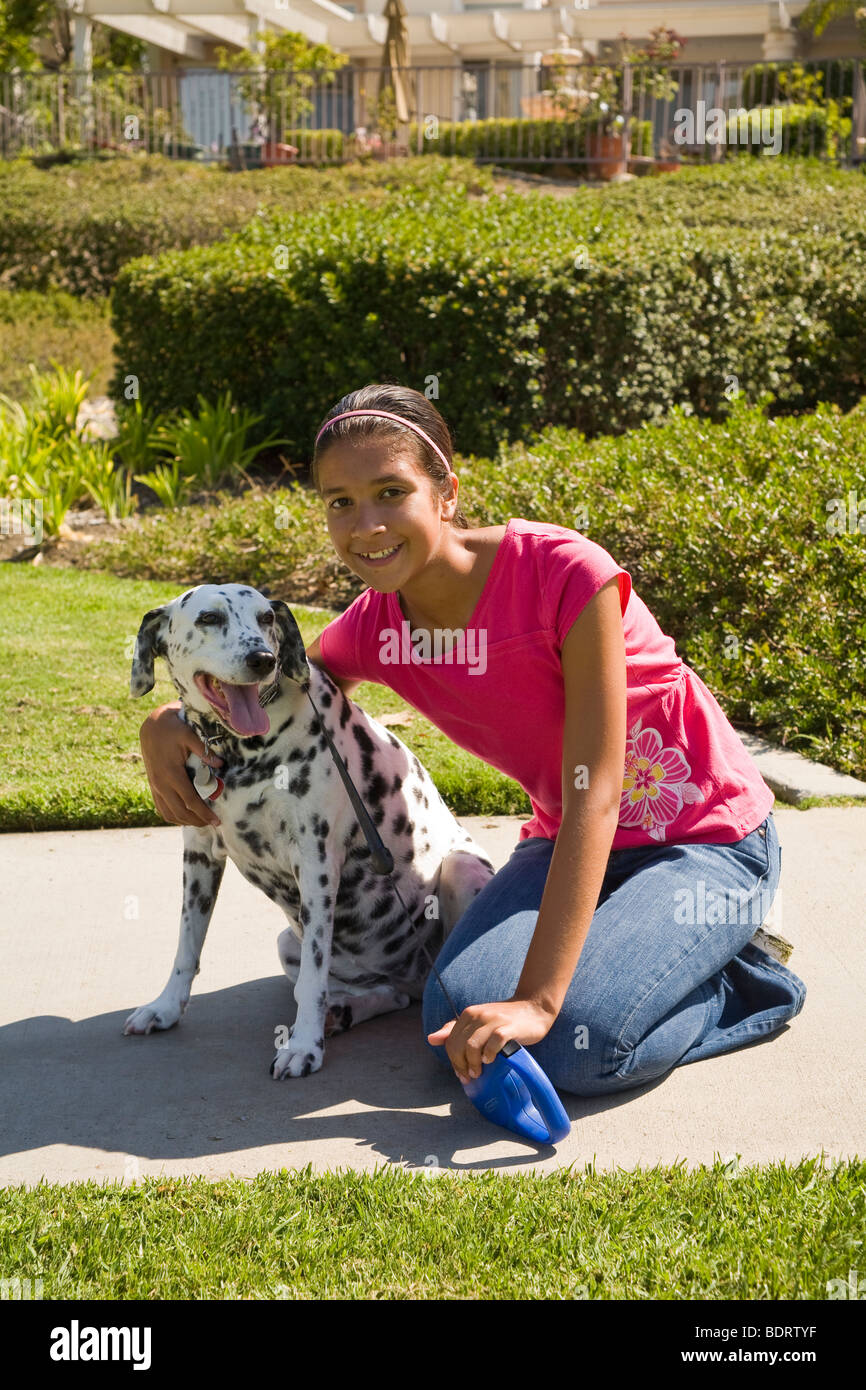 Hispanic American girl à 14 ans avec bras autour de hugging animal chien dalmatien propriétaire de contact visuel à la recherche de caméras à MR repéré spotty © Myrleen Pearson Banque D'Images