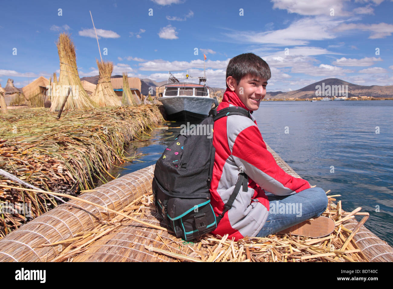 Teenage boy sur bateau fabriqué à partir de roseaux sur le lac Titicaca, Puno, Pérou Banque D'Images