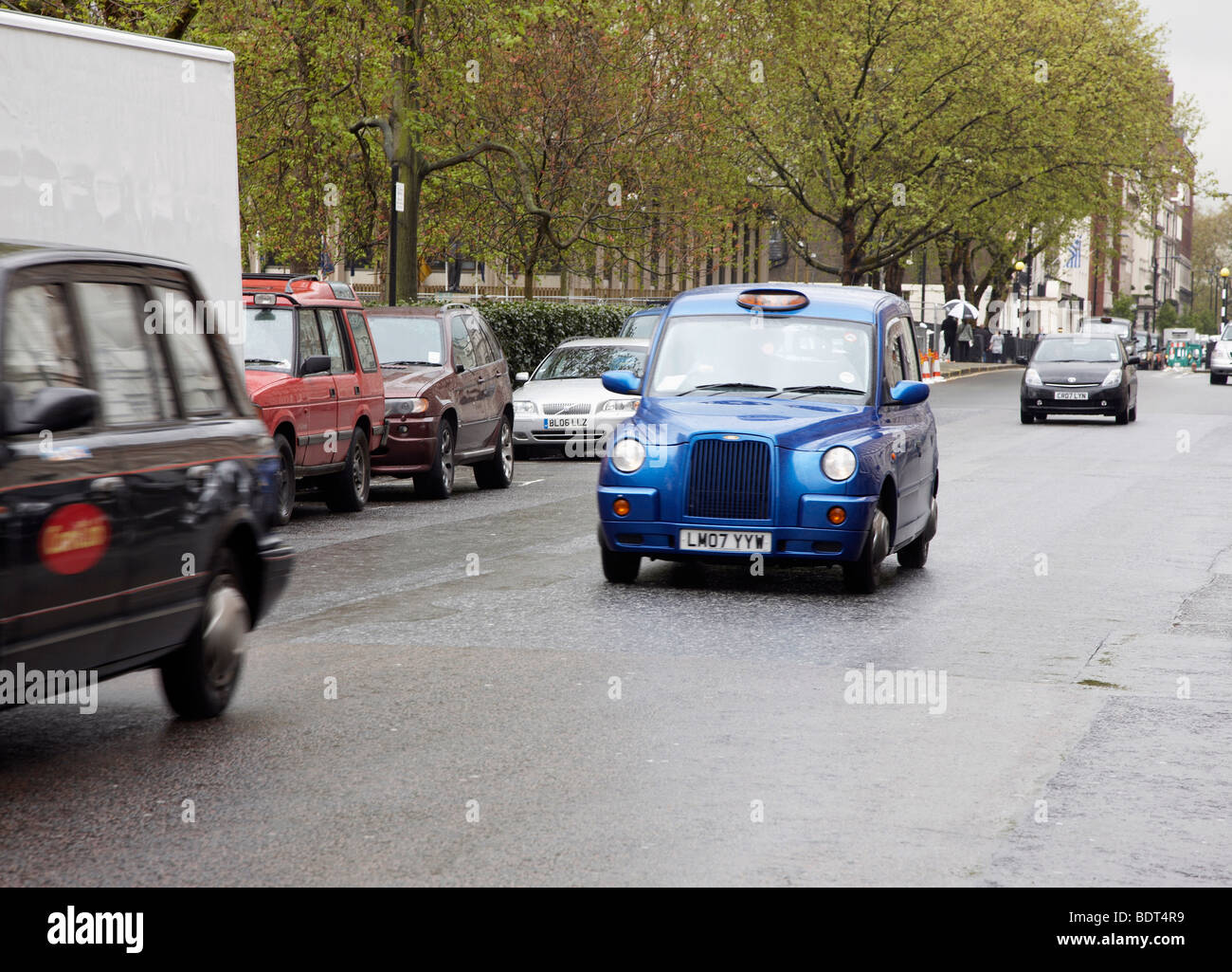 Les taxis noirs et bleus de la conduite sur Grosvenor Square Londres Banque D'Images