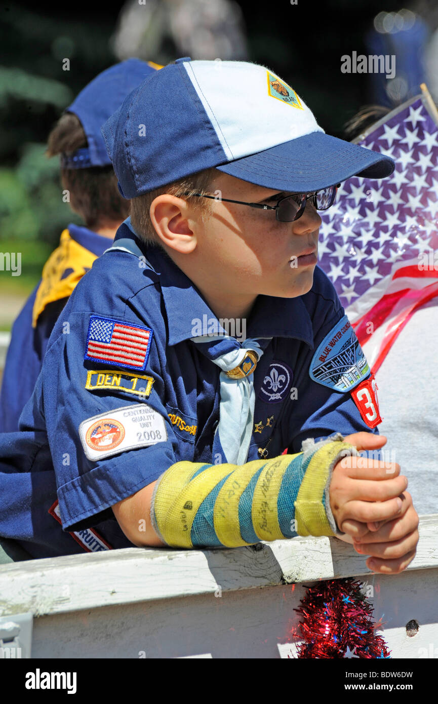Cub Scout dans défilé patriotique avec cast sur bras cassé Banque D'Images