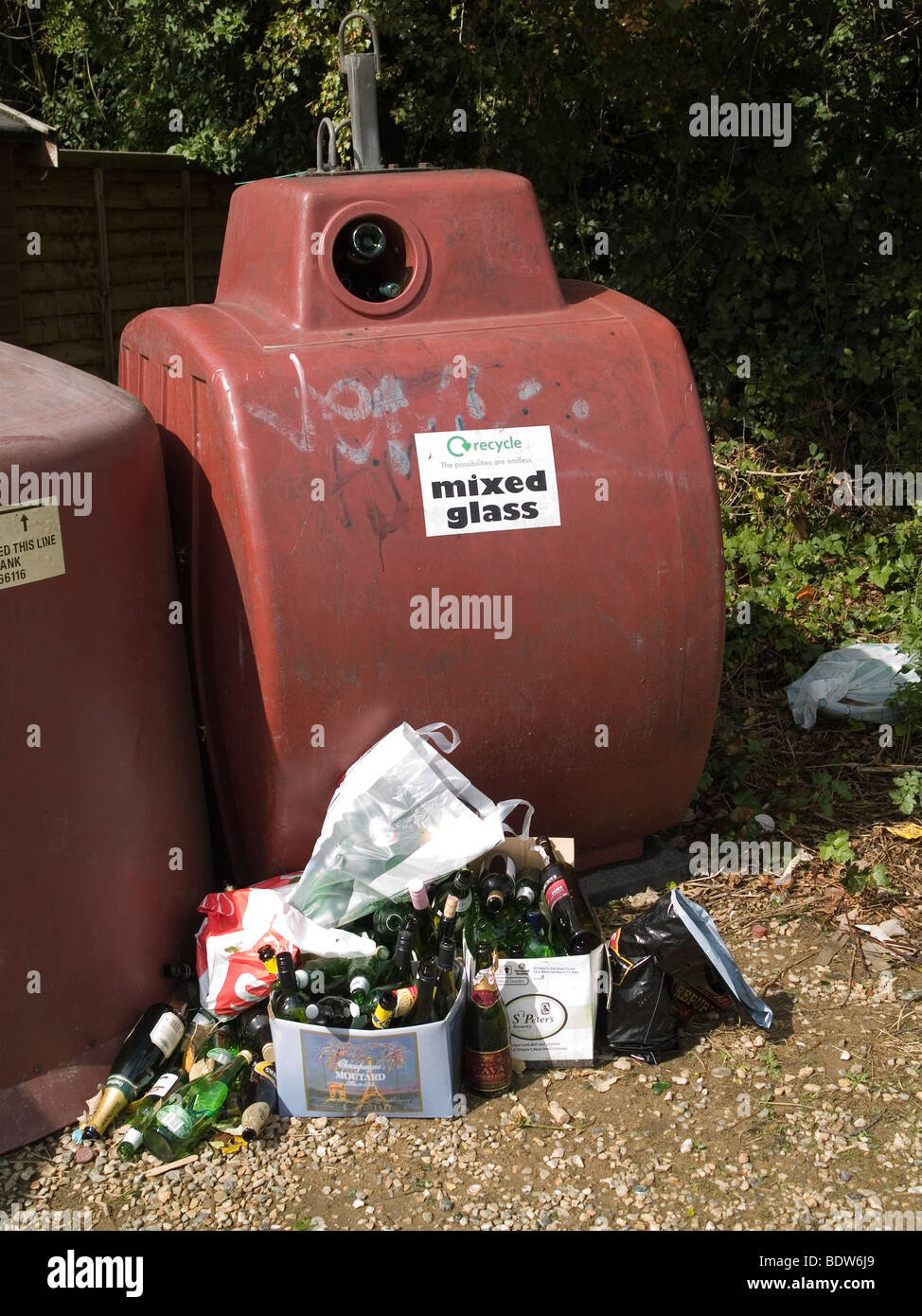 Bac de recyclage pour le verre mélangé trop remplis et avec des bouteilles entassées à côté Banque D'Images