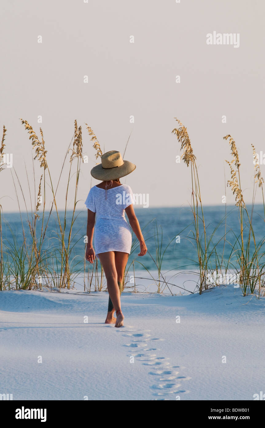 Jeune femme en marchant sur la plage de sable blanc fin de l'après-midi au coucher du soleil sur la Côte d'émeraude de Destin sur le golfe du Mexique. Banque D'Images