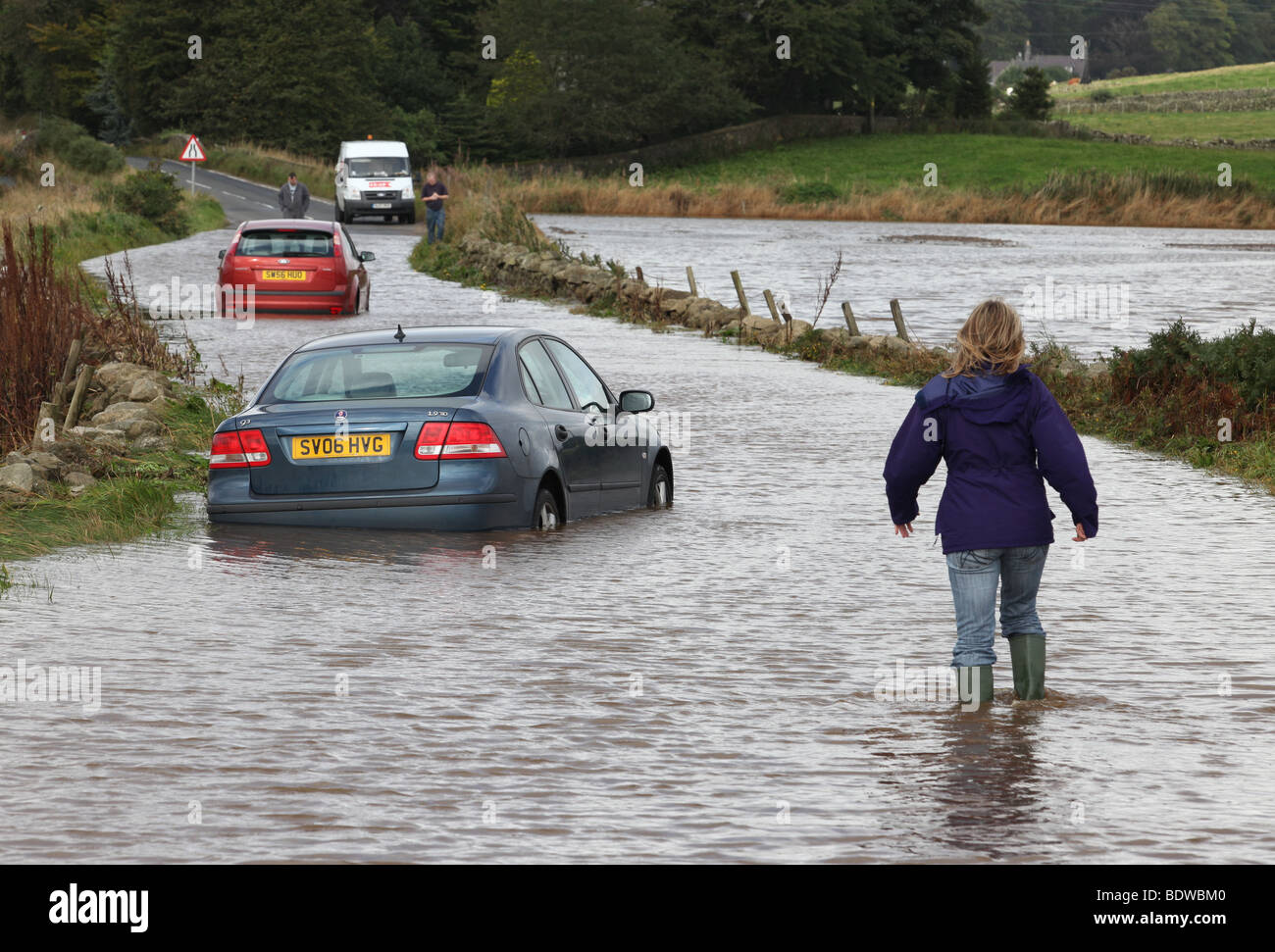 Femme patauge à voitures abandonnés après avoir été capturés dans les eaux de crue sur les routes près de Aberdeen, Écosse, Royaume-Uni, après de fortes pluies Banque D'Images
