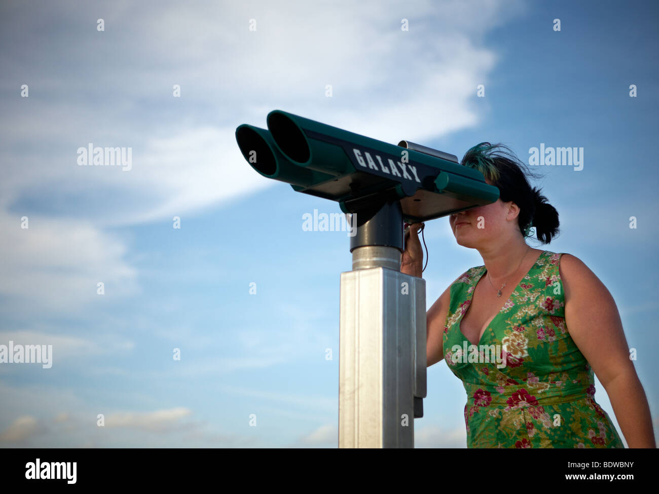 Une femme regarde à travers des jumelles télescope au soir en lumière chez  le Gillieux, sur la côte française Photo Stock - Alamy
