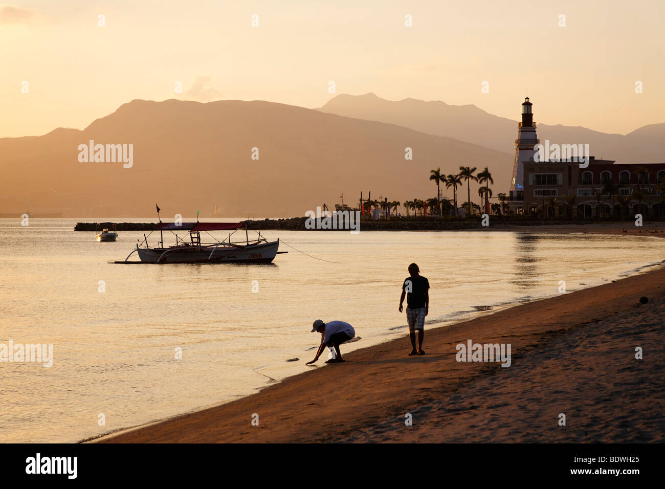 Les gens qui marchent sur la plage le soir, phare, bateau, banka, palmiers, d'humeur romantique, Olongapo City, Subic Bay, Luzon Banque D'Images