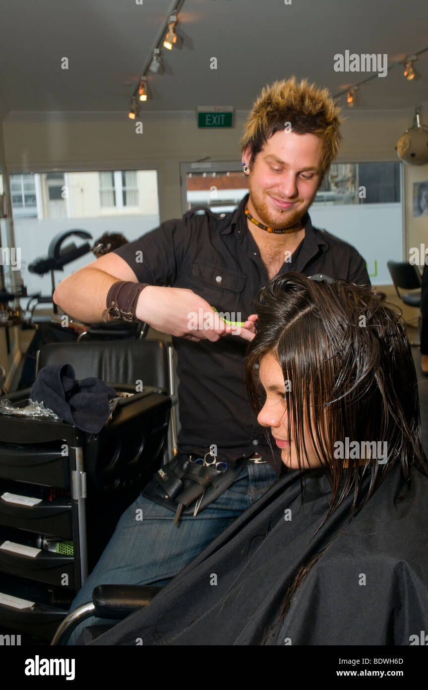 Un adolescent se fait couper les cheveux par un coiffeur dans un salon de coiffure Banque D'Images