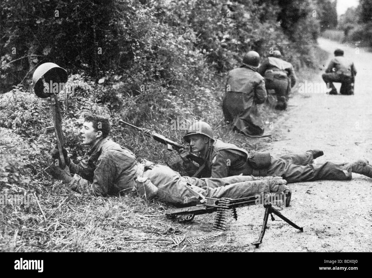 D-Day soldat américain tente de débusquer l'ennemi par attirer le feu le long de la hedgrows mortelle près de Carentan, France, en juin 1944 Banque D'Images