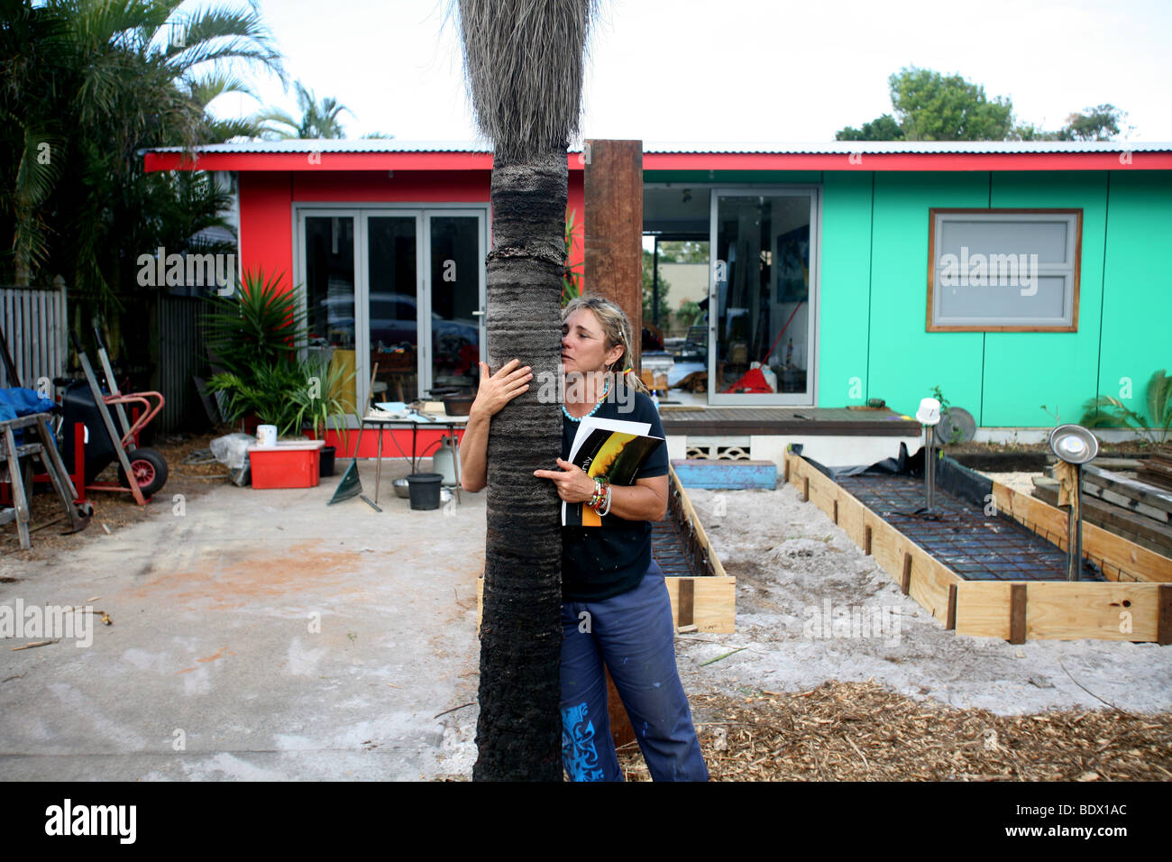 Une femme embrasse un arbre Pâturin en face de sa maison. Banque D'Images
