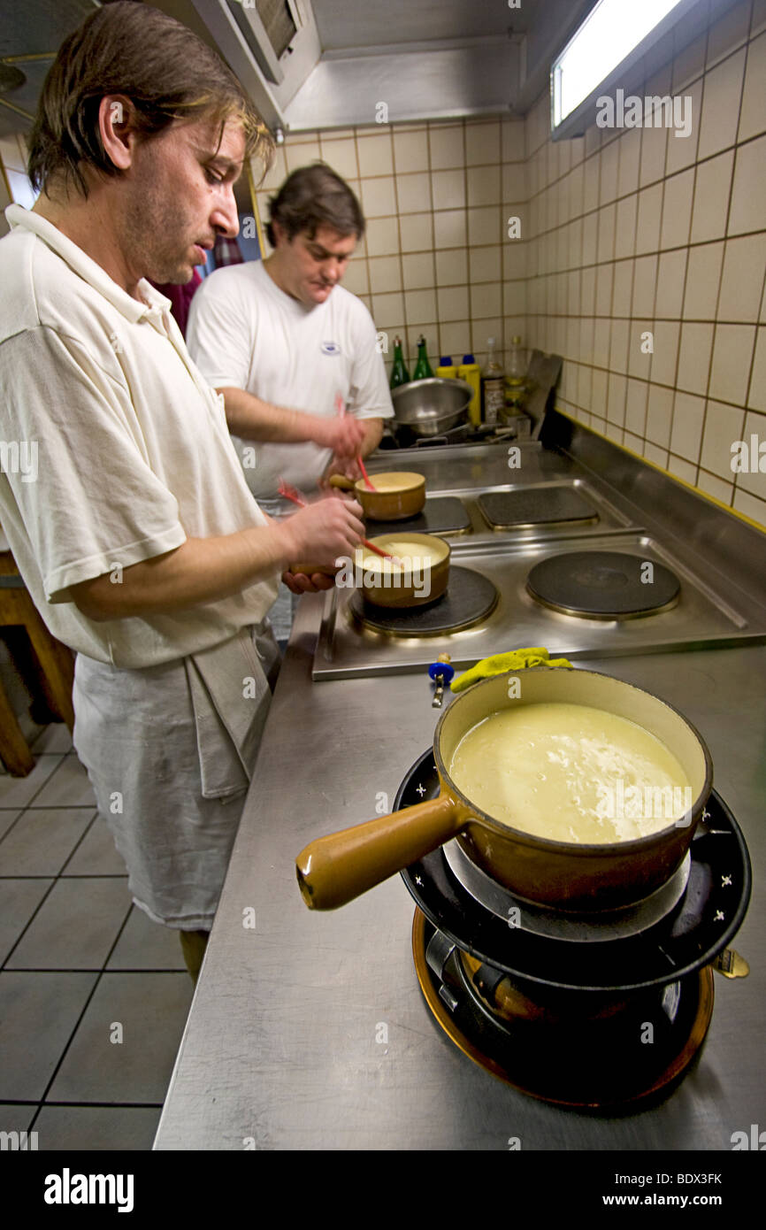 Les cuisiniers préparent fondue dans un restaurant à Loèche-les-Bains, un village de haute montagne à la lisière sud de la Suisse. Banque D'Images