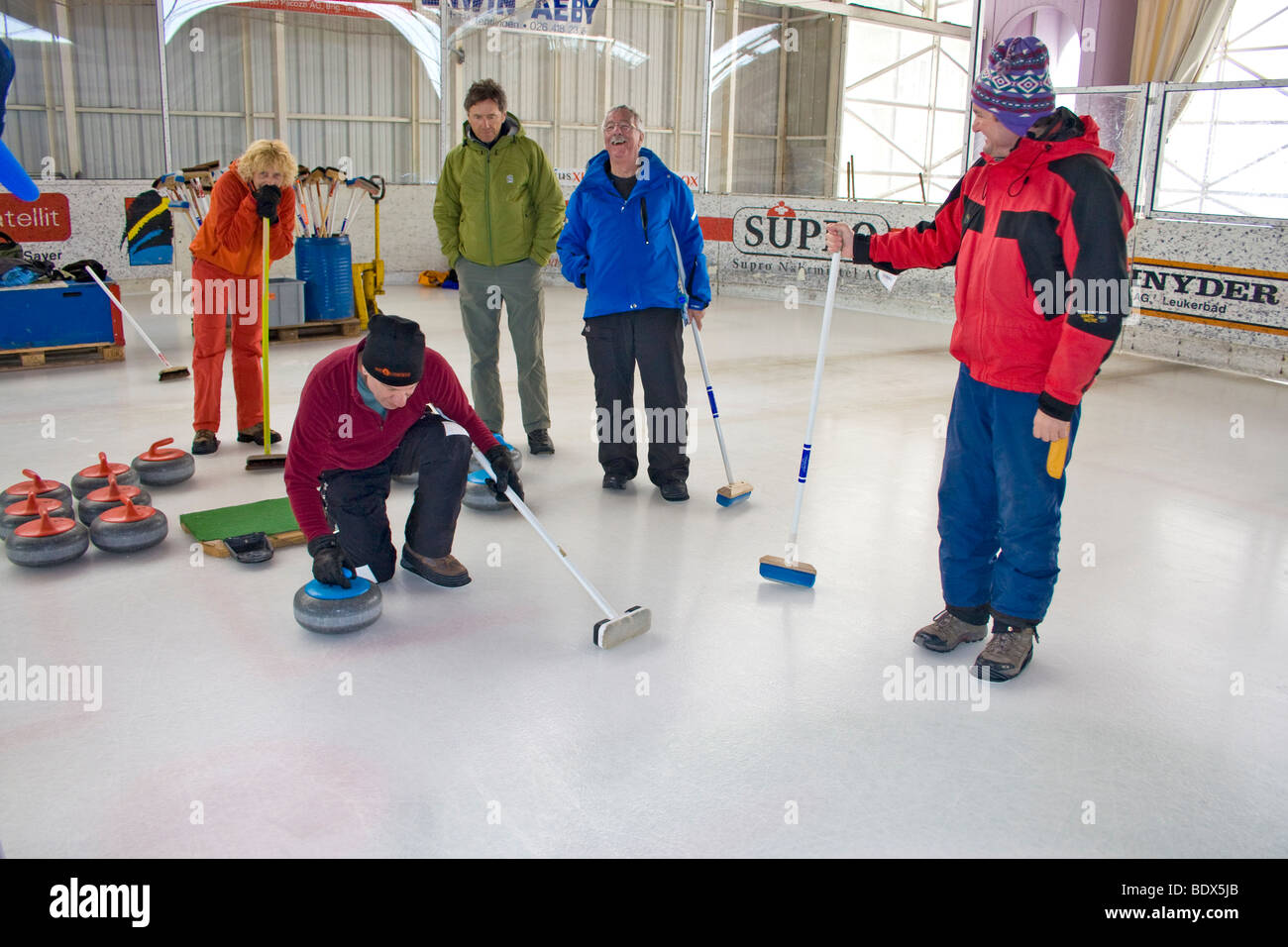 Les visiteurs de Swiss village essayez de curling à la patinoire locale. Banque D'Images