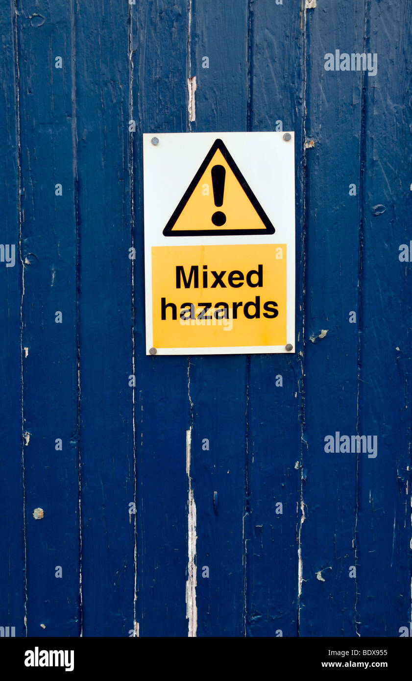 Une porte en bois bleu avec un panneau d'avertissement de dangers "mixtes". Banque D'Images