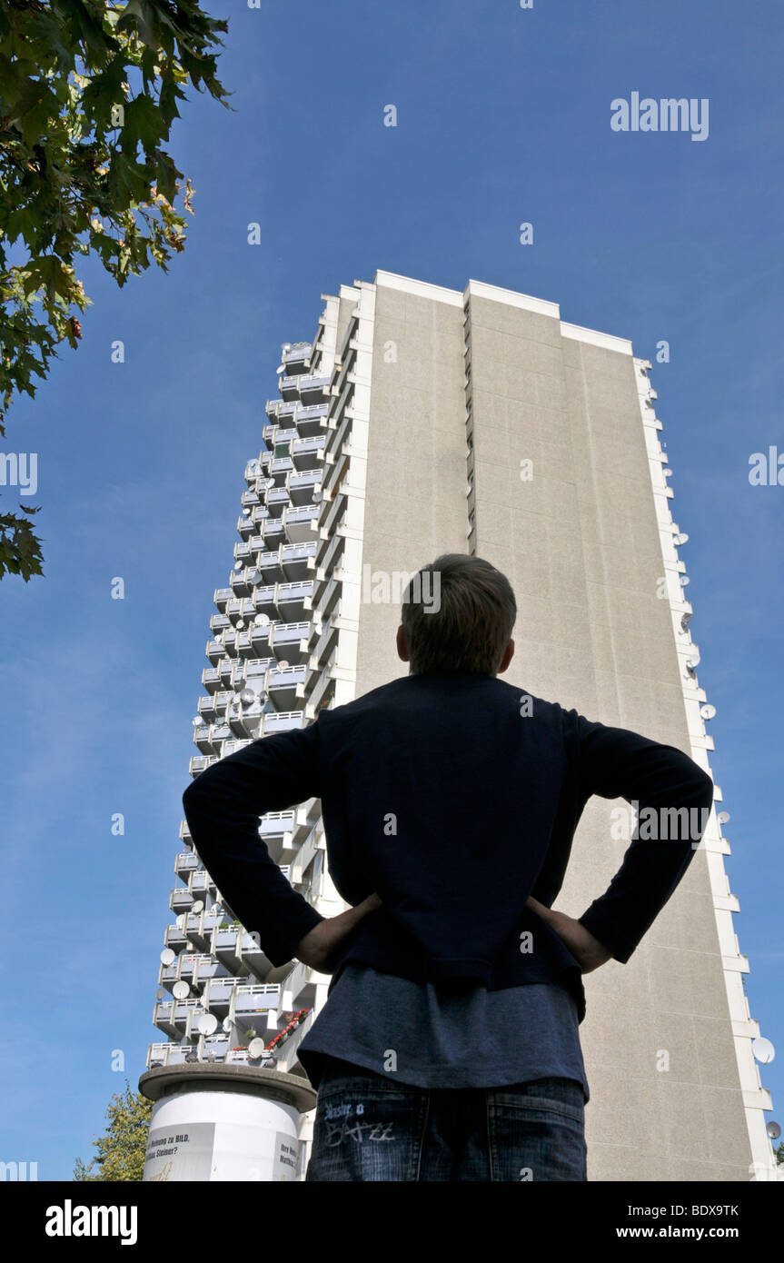 Garçon debout en face d'une tour d'habitation avec des balcons et des antennes paraboliques, ville satellite de Chorweiler en coopération Banque D'Images