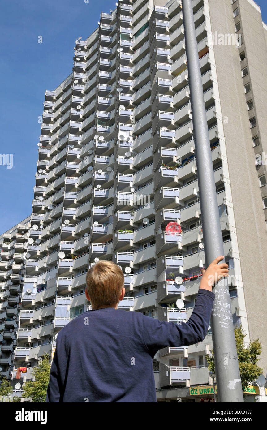 Garçon debout en face d'une tour d'habitation avec des balcons et des antennes paraboliques, ville satellite de Chorweiler en coopération Banque D'Images