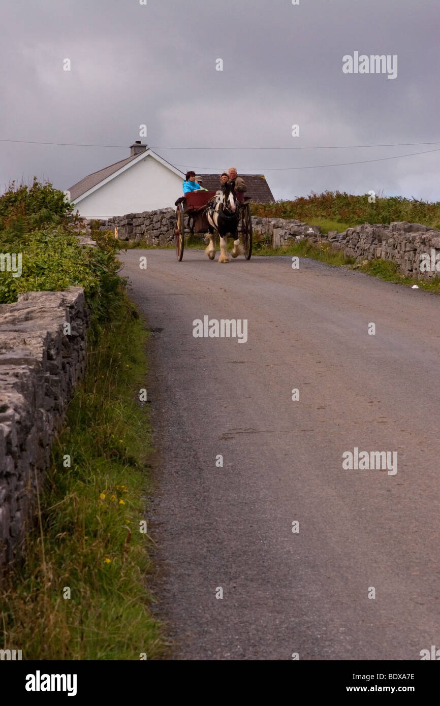 Un chariot se déplace le long d'un mur de pierre sur la route bordée d'Inis Mor (Inismore) Island, les îles d'Aran, Co. de Galway, Irlande Banque D'Images
